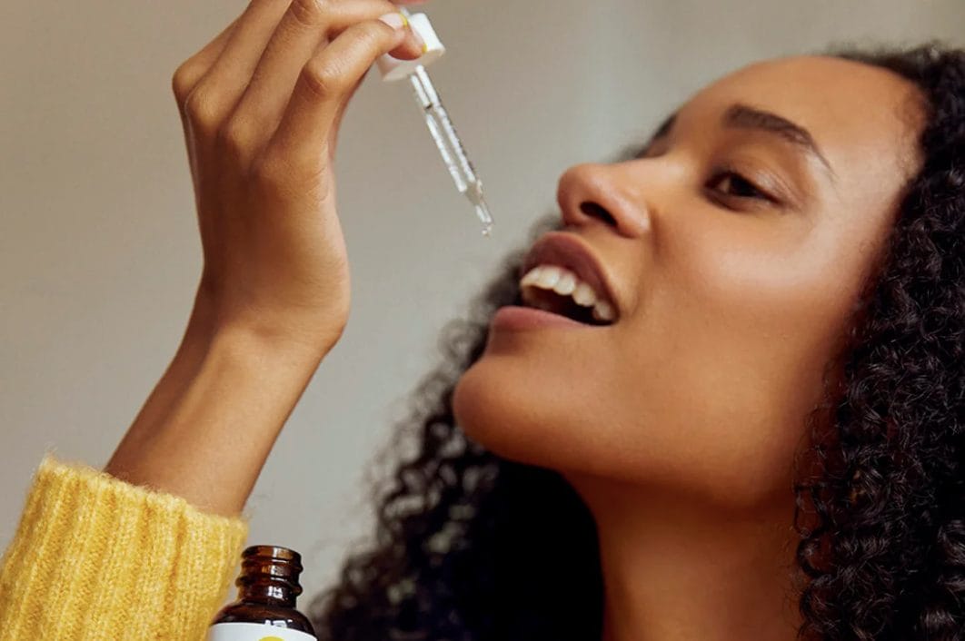 A woman taking a drop of CBD Oil on her tongue