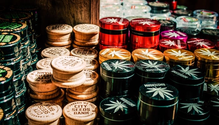 A shelf in a local cannabis shop stocked with purchasable cannabis grinders that have branding and logos on them.