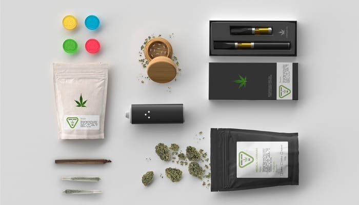 A selection of cannabis products, including a vape cartridge, grinder, and electronic cigarette, laid out on a white surface.
