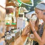Two female tourists are shopping for marijuana at a legal cannabis shop, and one of them is smelling the product.