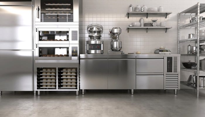 A kitchen contains modern stainless steel appliances, including mixers, ovens, freezers, scales and more.